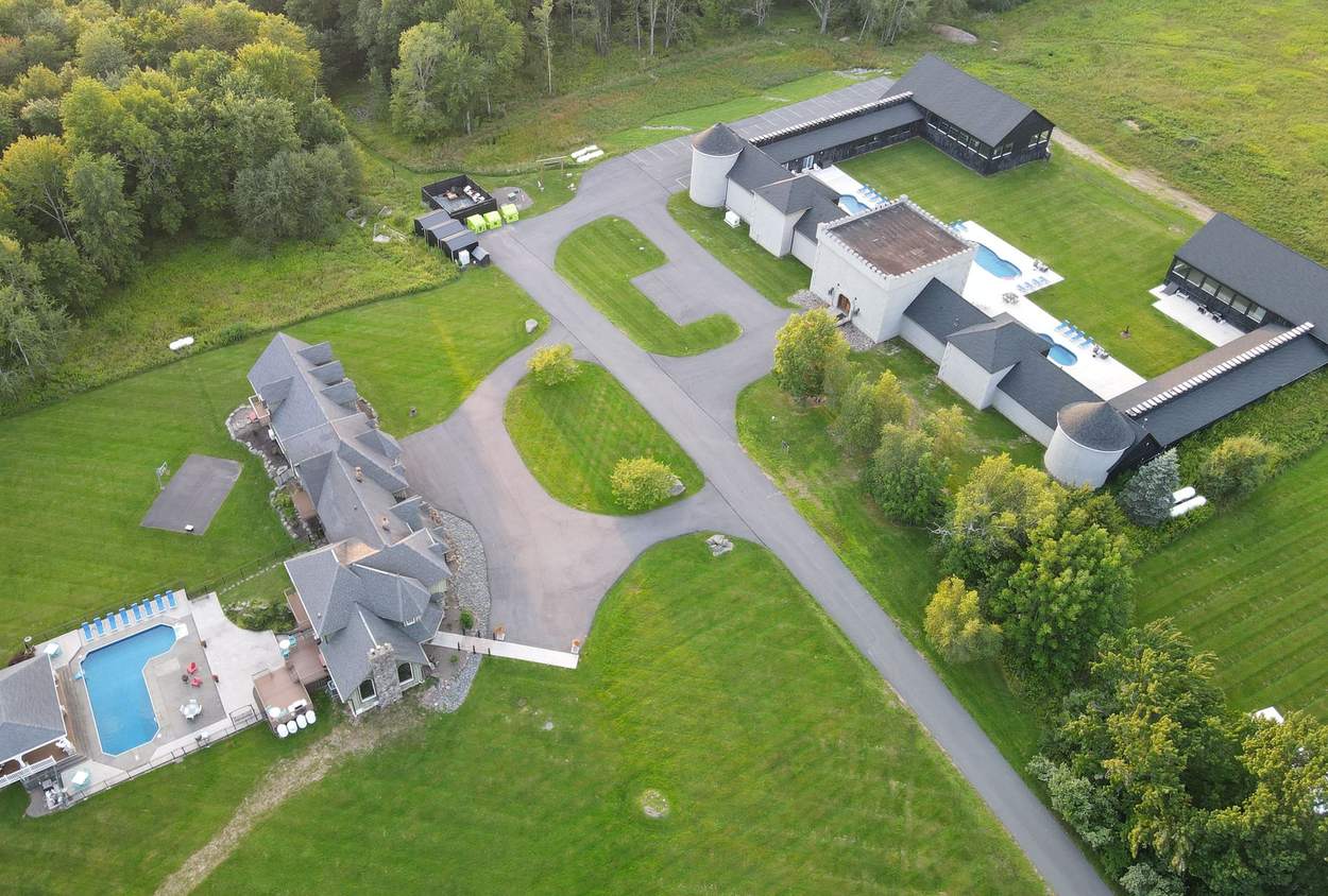 Aerial view of the Hilltop compound: the Castle and its pools on one side of the drive, the Mansion on the other, surrounded by woods and open lawn