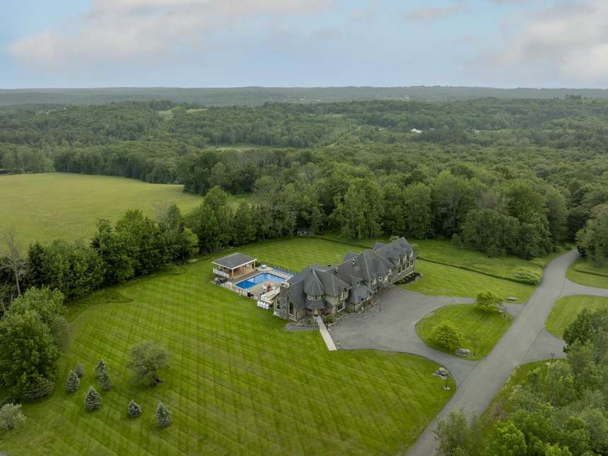 The Mansion from the air, its pool and covered pavilion beside it and open fields and woodland beyond