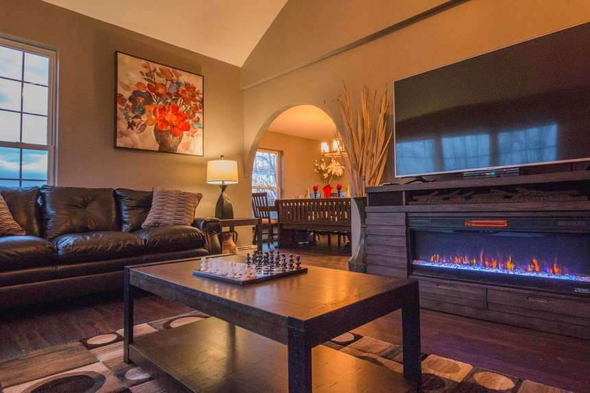 The Lodge living room at Hilltop, leather seating and a long fireplace lit in the evening