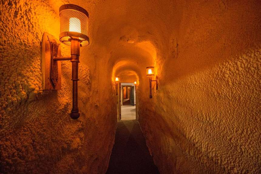 A torch-lit stone tunnel running beneath the Castle